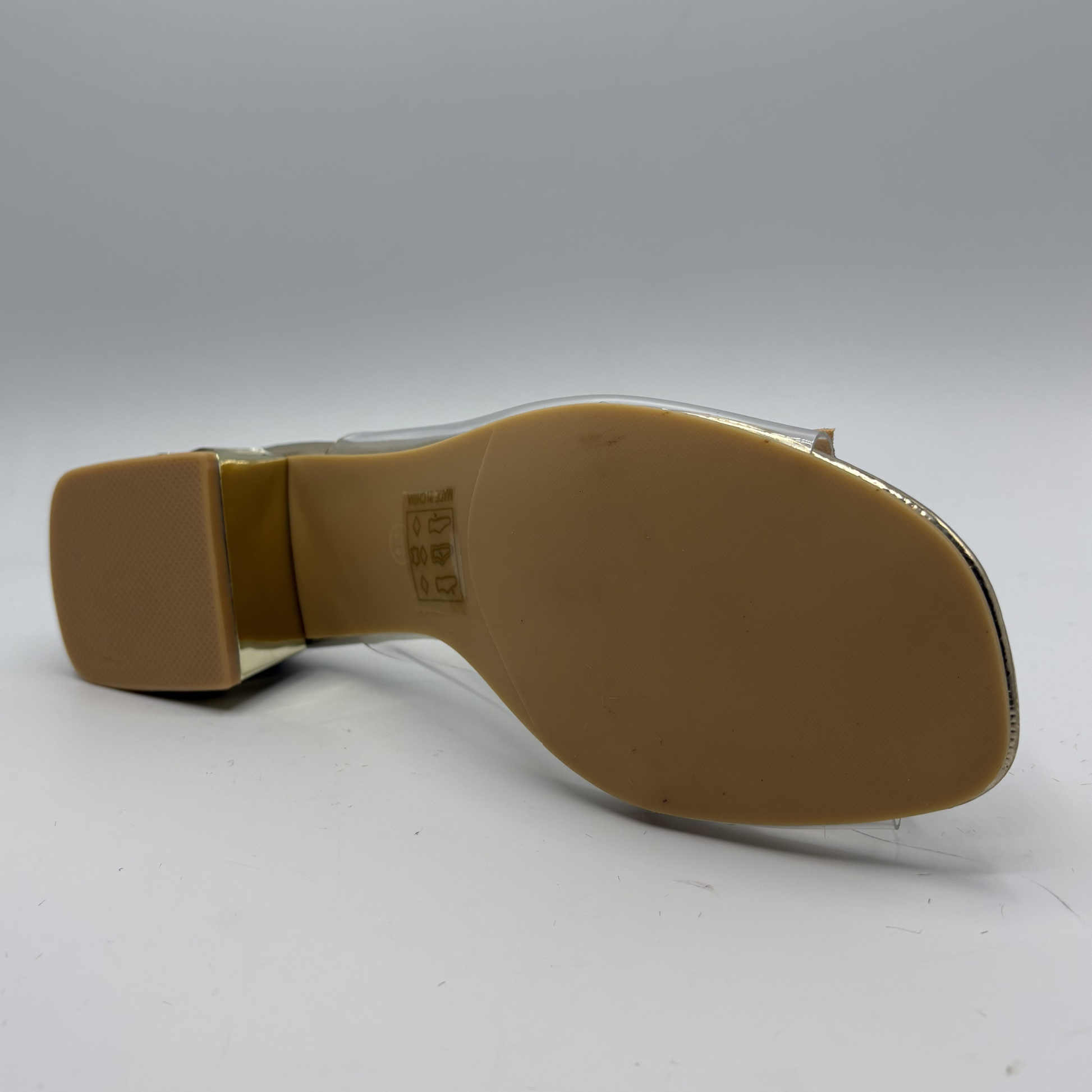 Clear sandal with decorative strap and low heel on a gray background