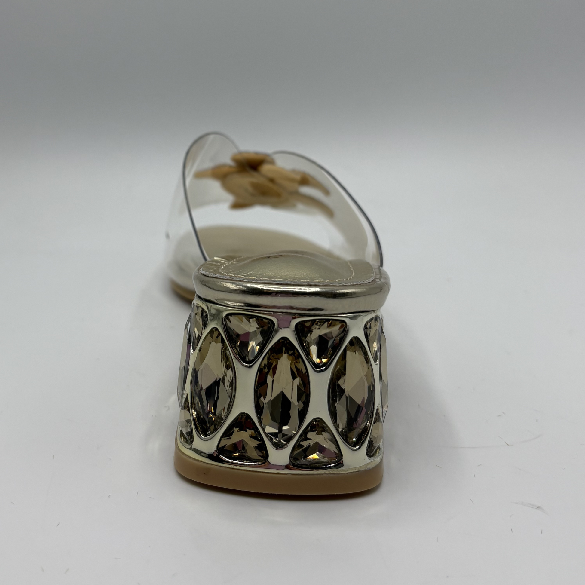 Clear sandal with decorative strap and low heel on a gray background