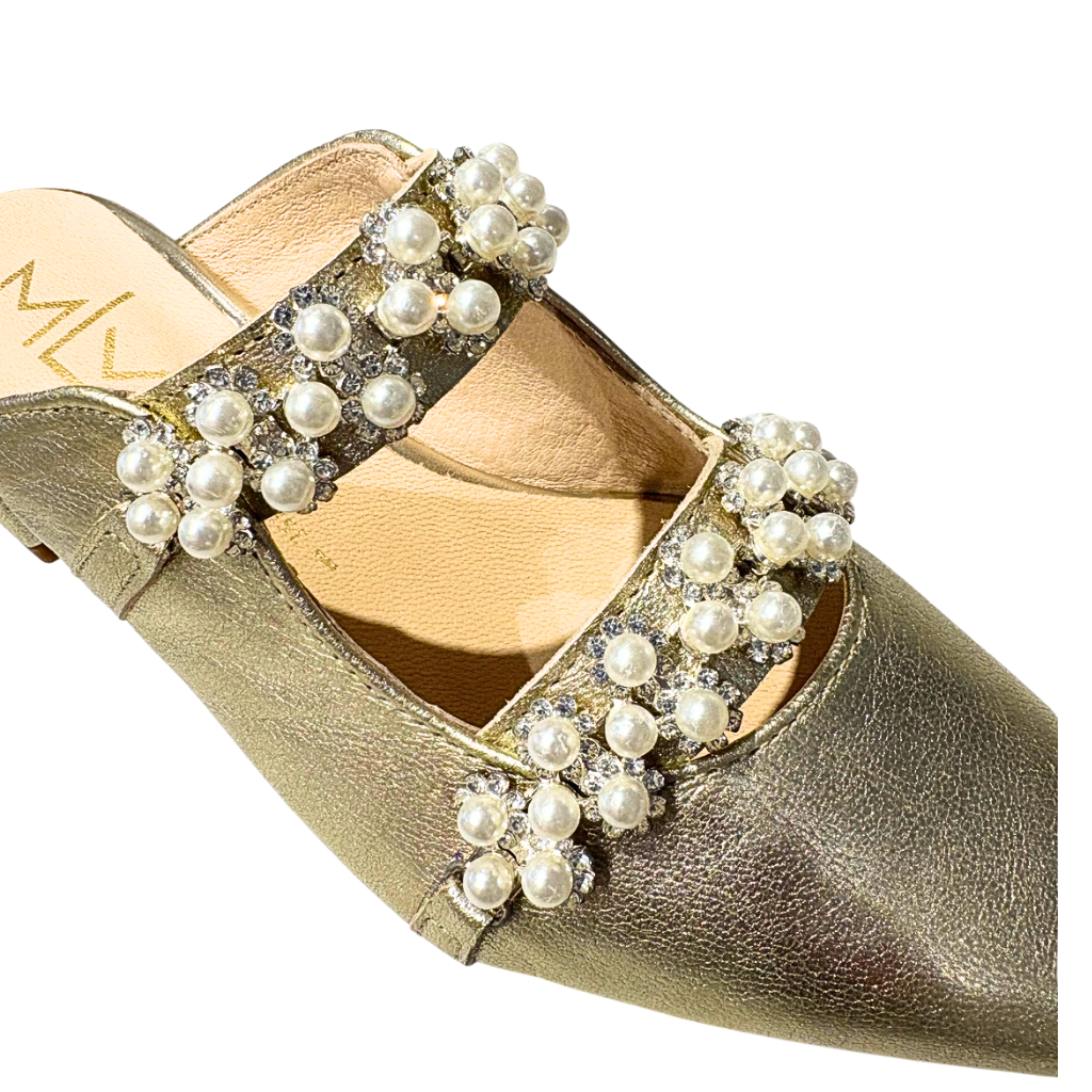 Close up of a champagne gold shoe with pearl and crystal embellishments on a white background
