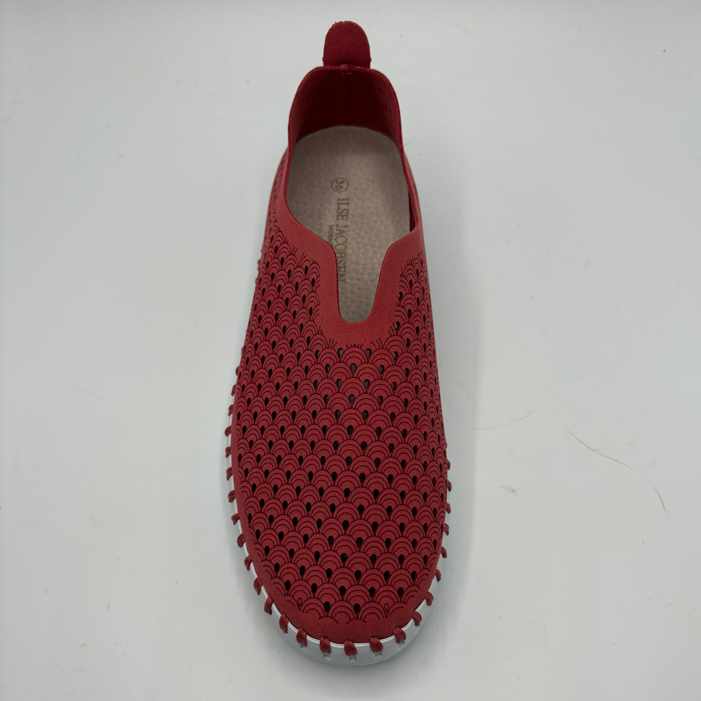 Red slip-on shoe with textured sole on a white background