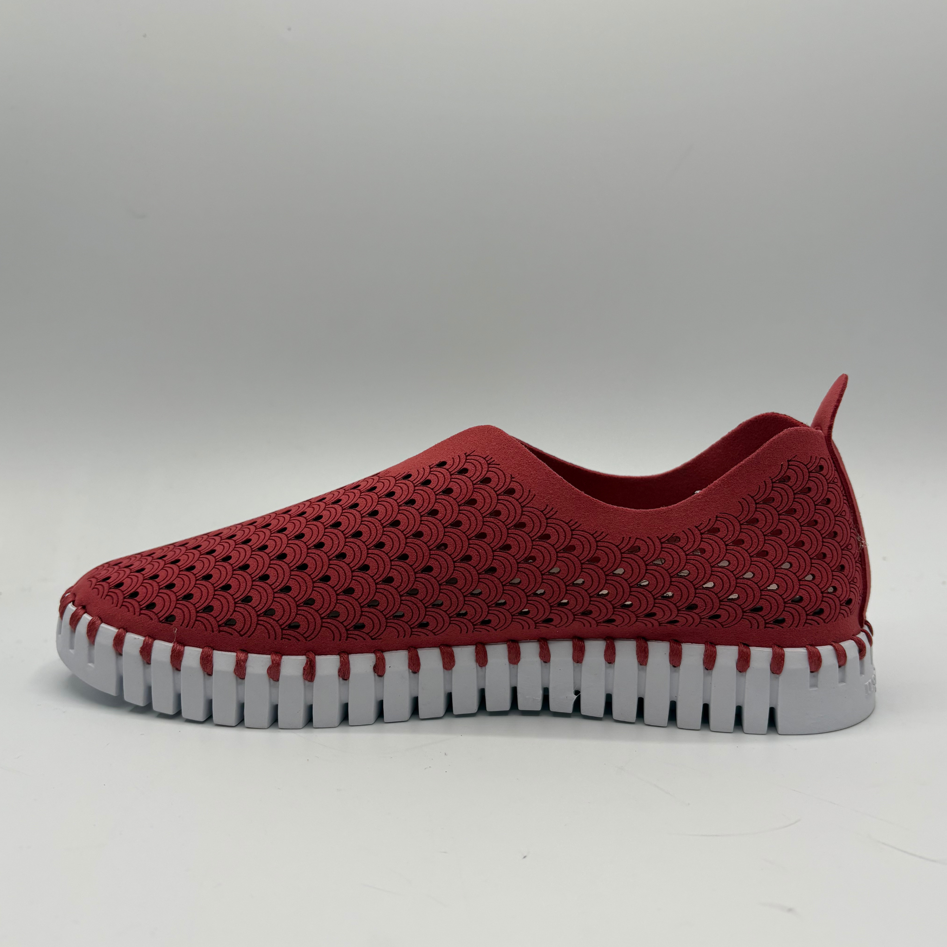 Red slip-on shoe with a white sole on a gray background