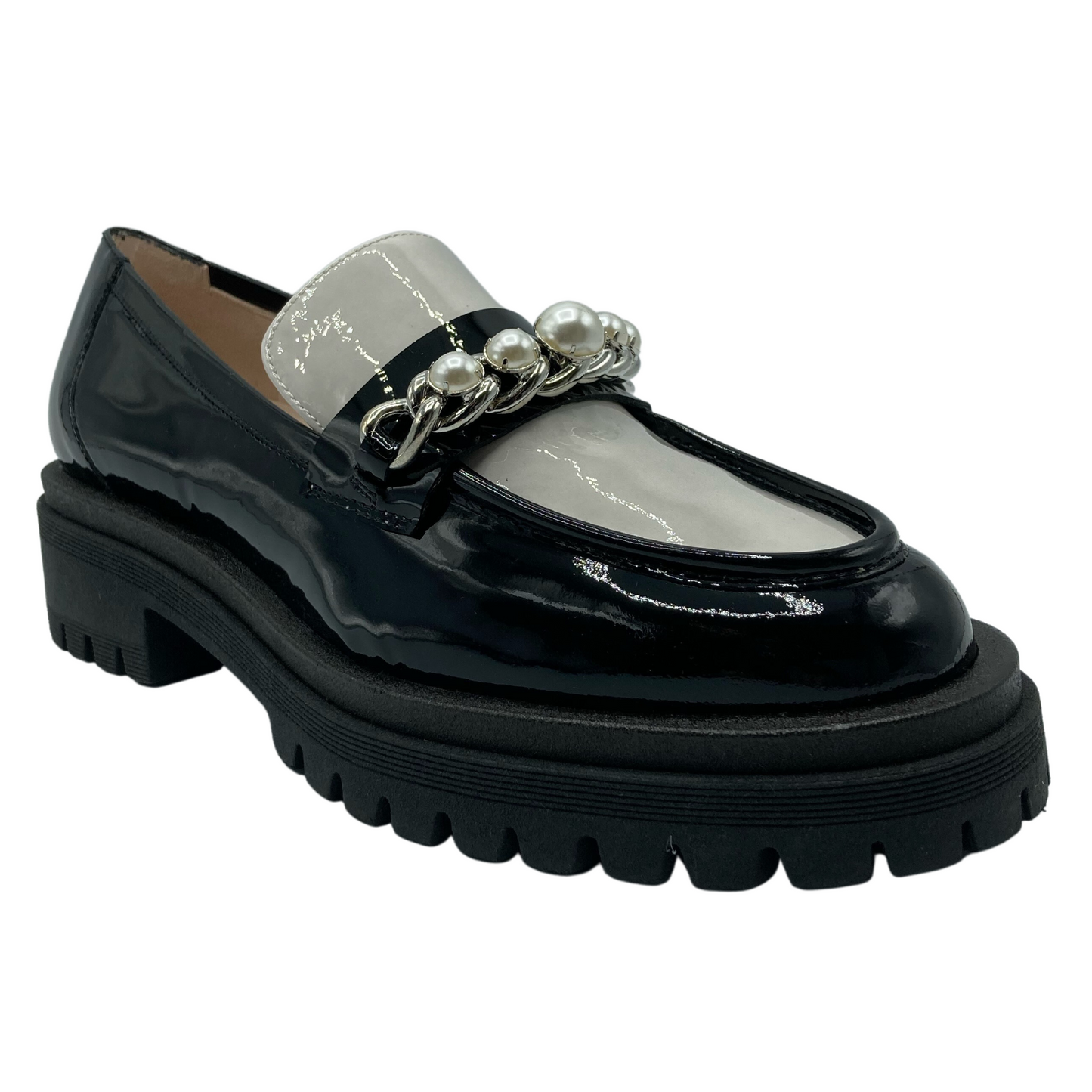 45 degree angled view of patent leather loafer with black and white upper. Lug rubber outsole and pearl and chain detail on the upper