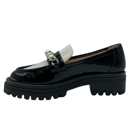 Left facing view of black and white patent leather loafer with pearl and chain detail on upper and rubber lug sole