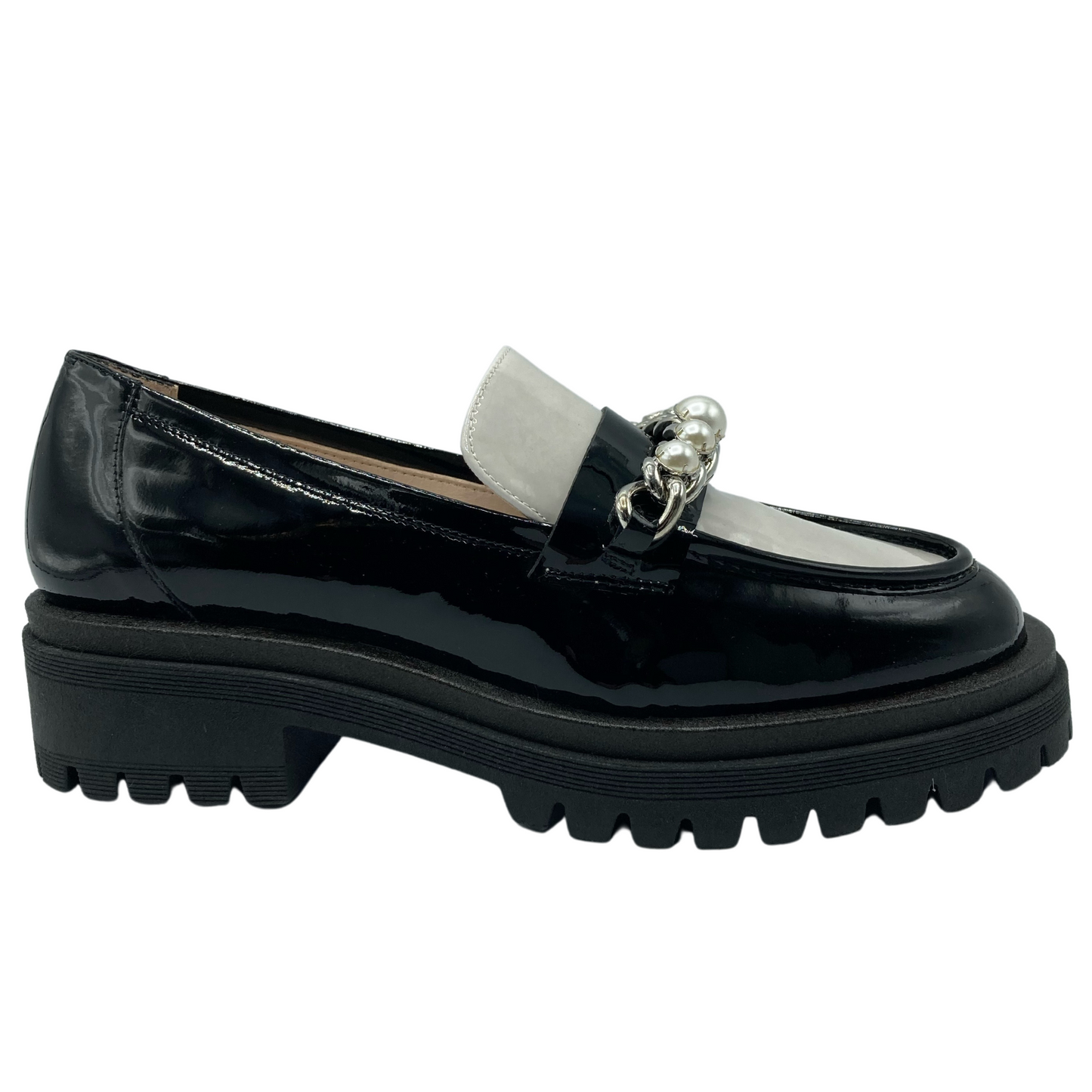 Right facing view of black and white patent leather loafer with rubber lug sole. Pearl and chain detail on upper