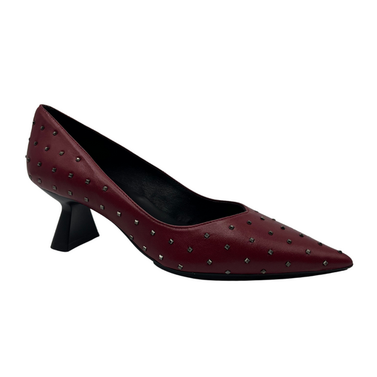 45 degree angled view of red leather pump with metallic studs and flared heel