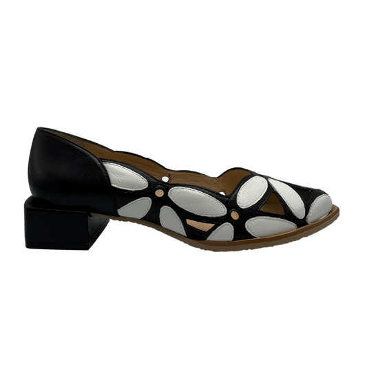 Right facing view of black and white leather shoe with a black short block heel and floral style appliques on upper.