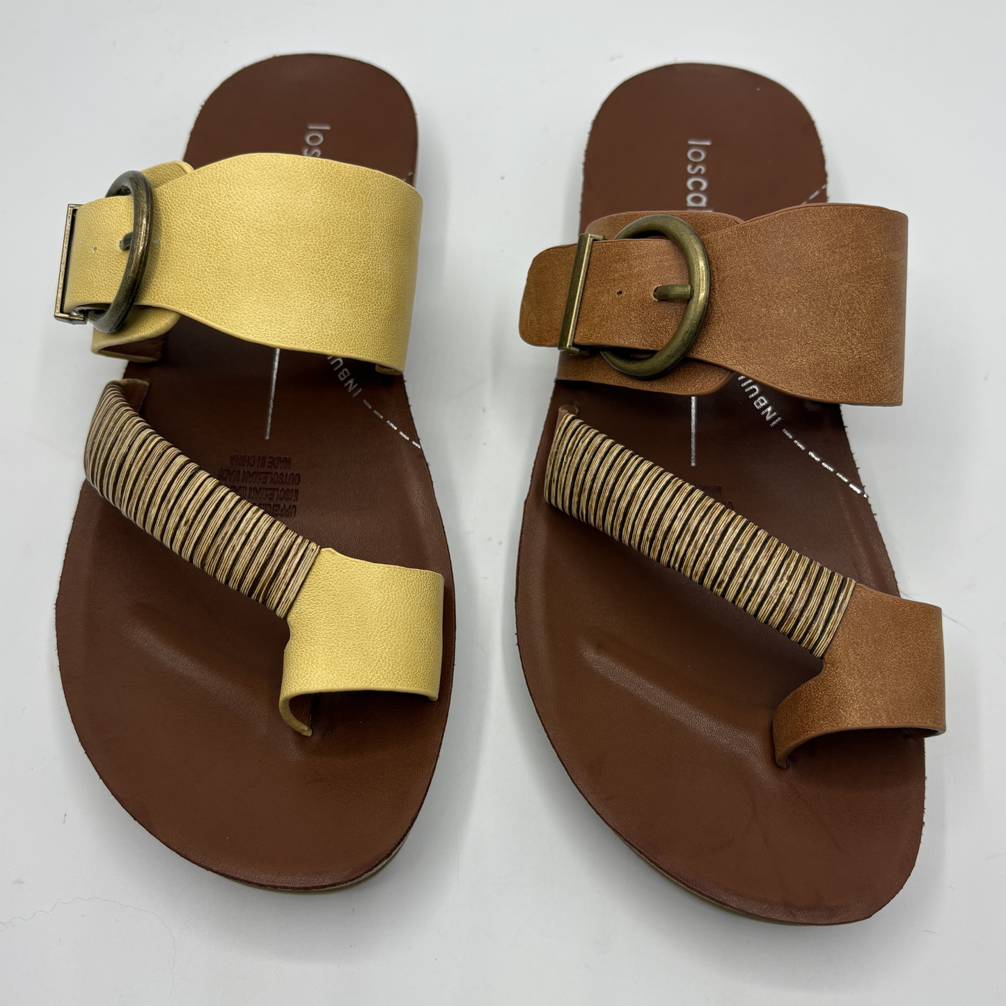 Pair of brown sandals with yellow and tan straps on a white background
