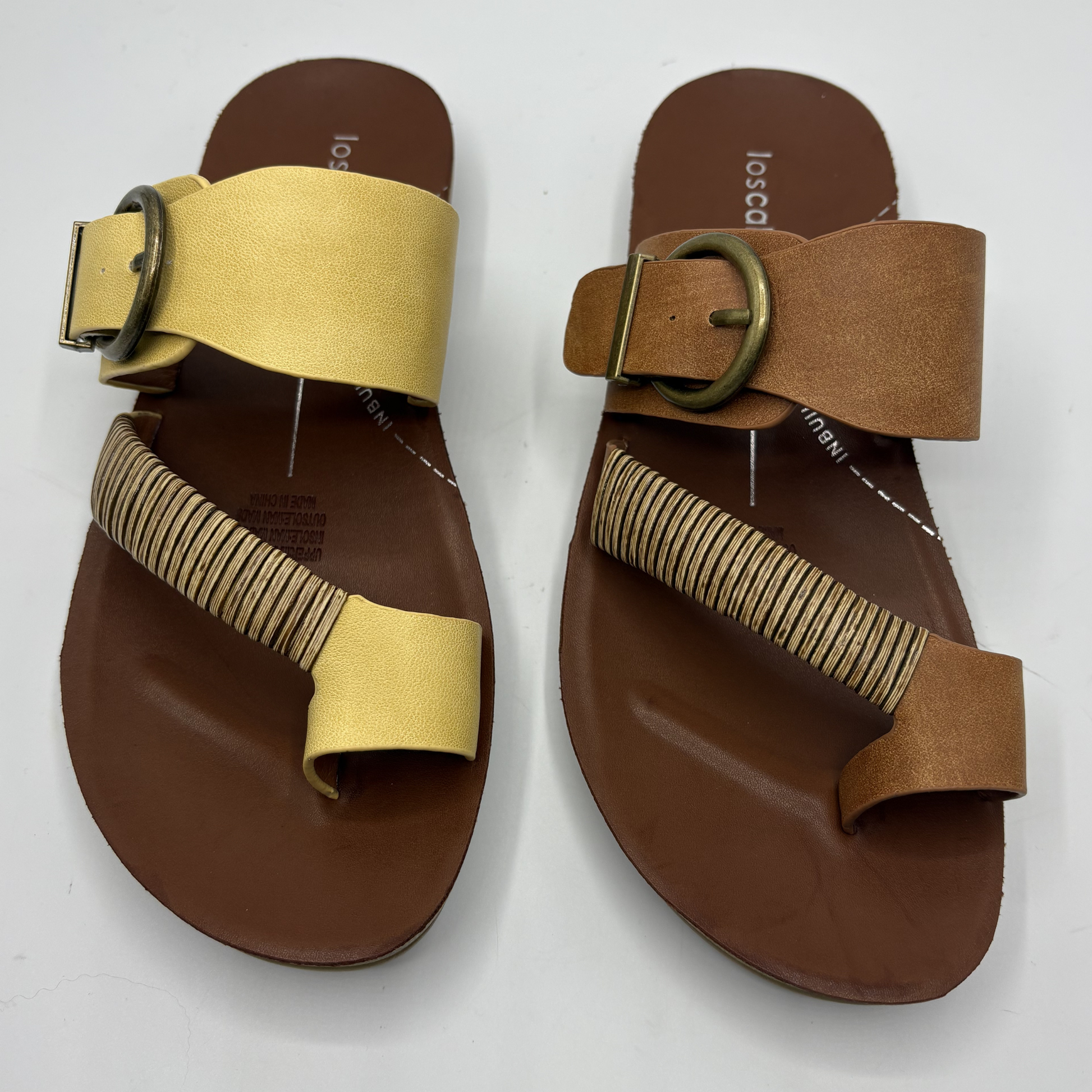 Pair of brown sandals with yellow and tan straps on a white background