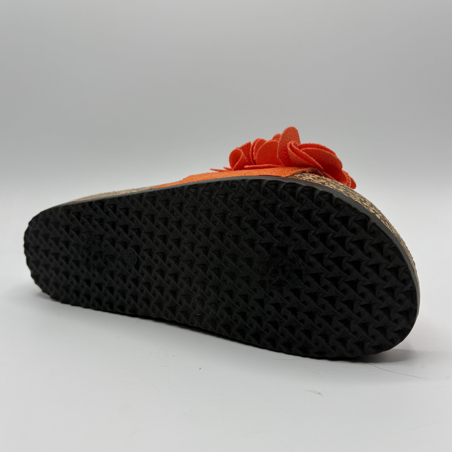 Orange sandal with a flower detail on a white background