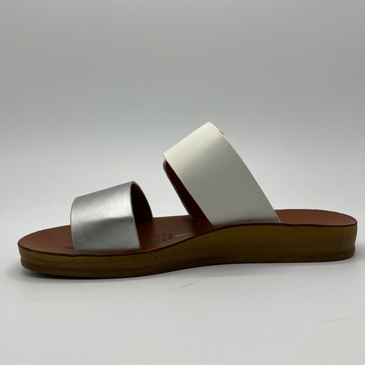 Left facing view of a two strapped sandal with one silver strap and one white strap. The white adjustable strap features a gold buckle and a flat outsole.