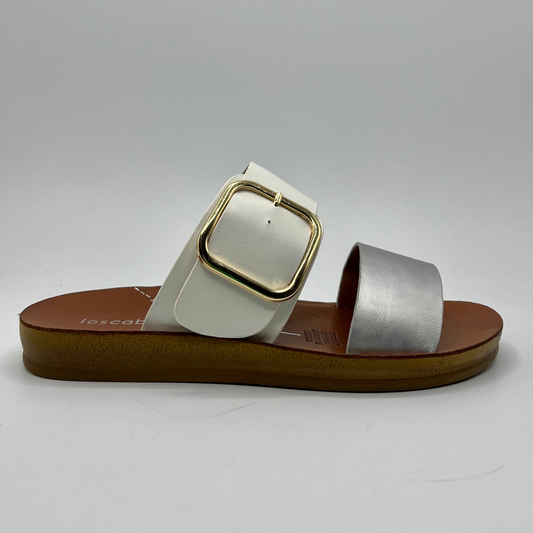 Right facing view of a two strapped sandal with one silver strap and one white strap. The white adjustable strap features a gold buckle and a flat outsole.