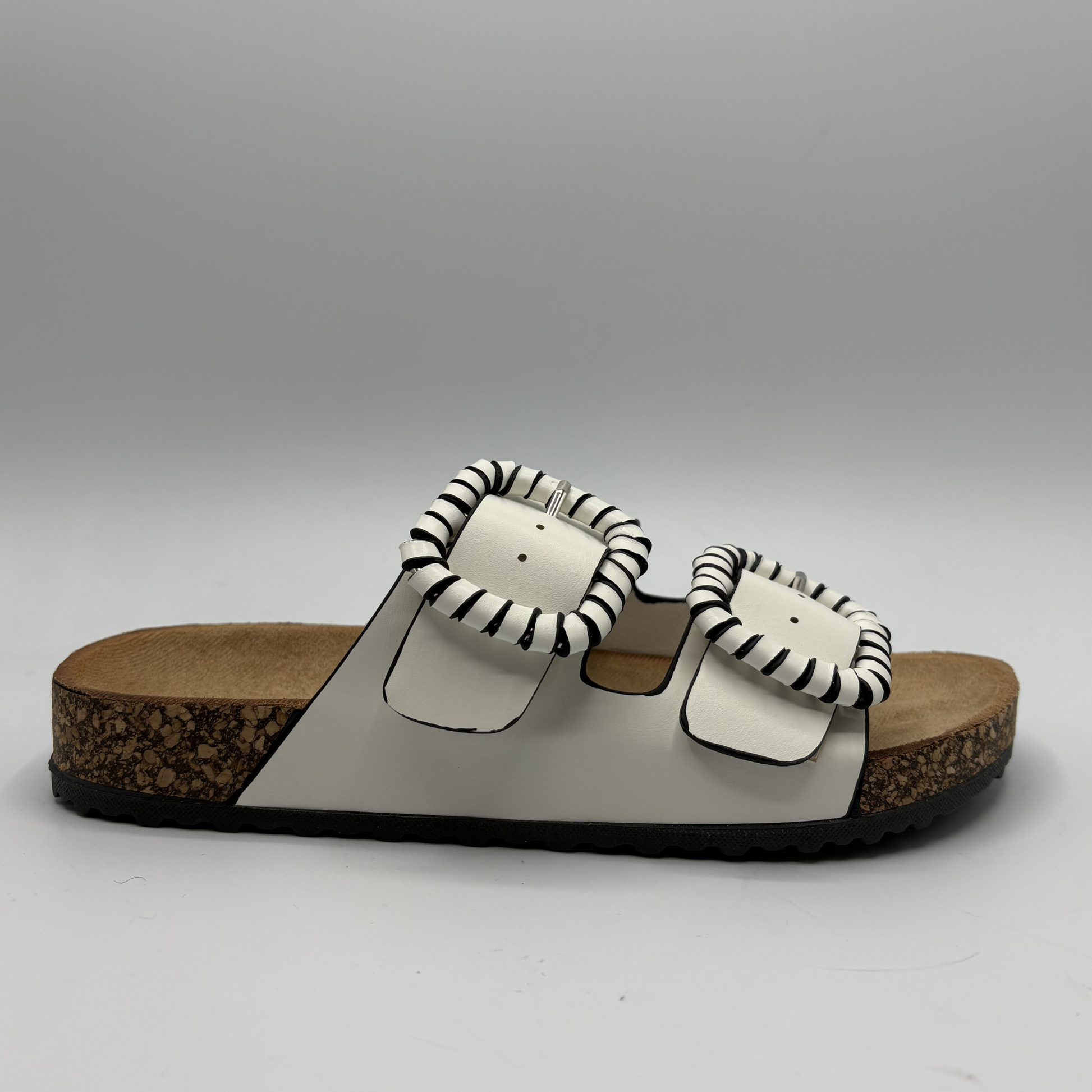 White sandals with striped pattern straps on a gray background