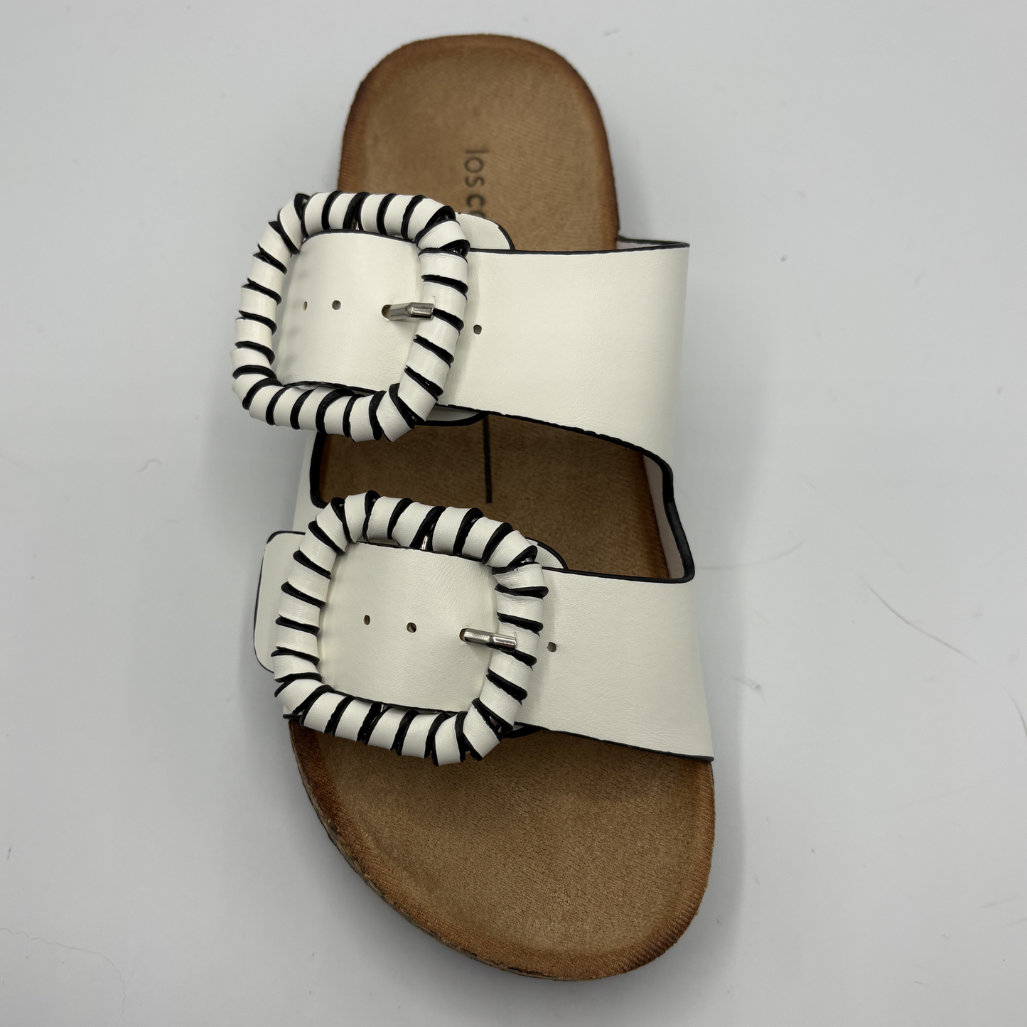 White sandal with stripe patterned straps on a light gray background