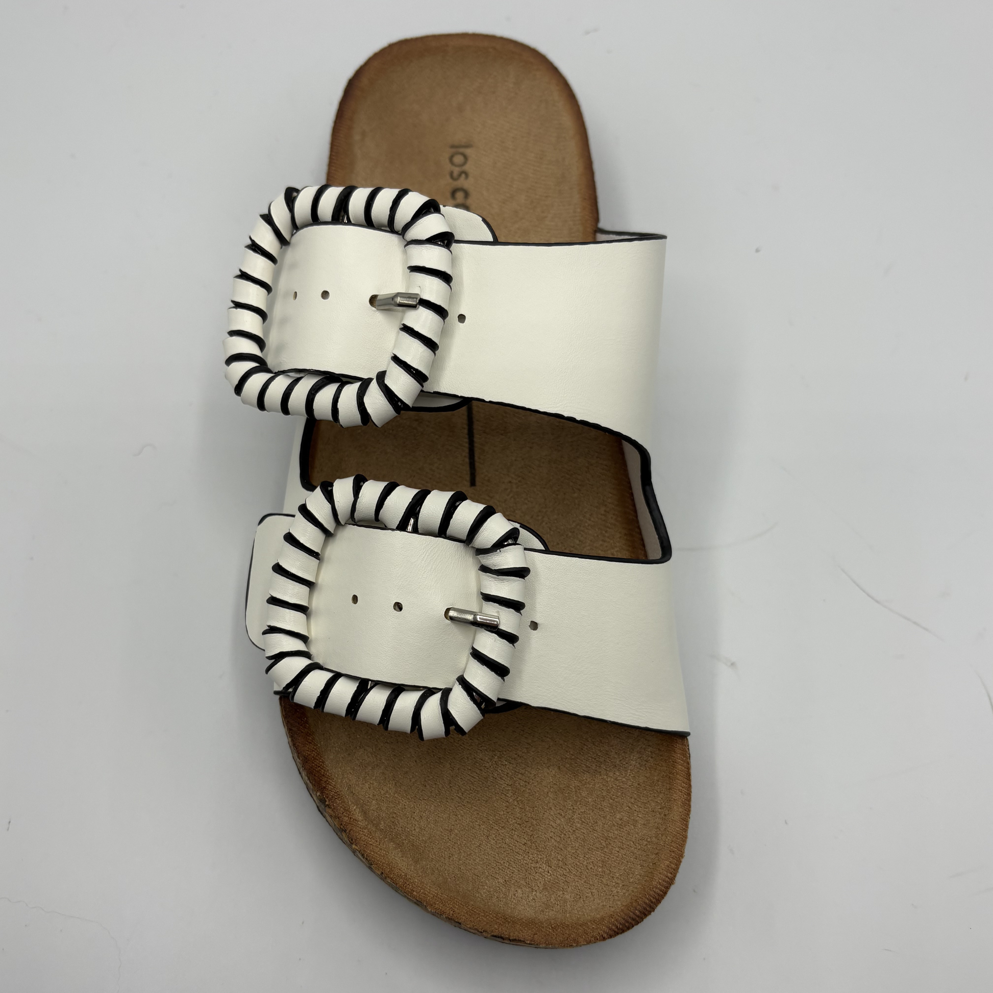 White sandal with stripe patterned straps on a light gray background