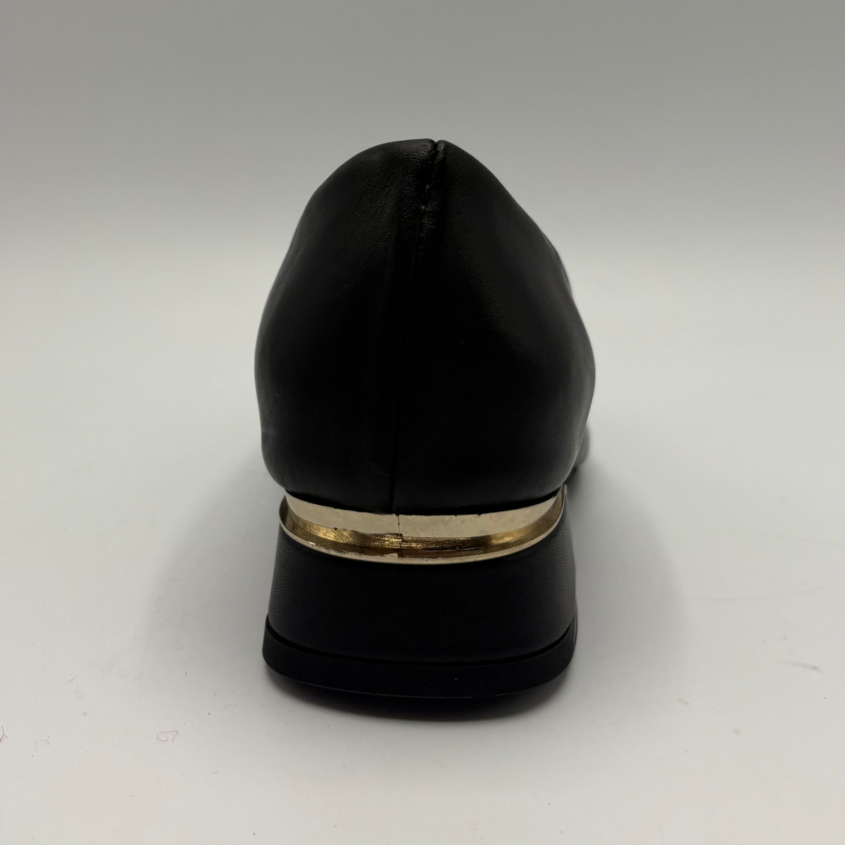 Back view of a black leather pump with a slouchy accent on the pointed toe and a gold accent on the heel