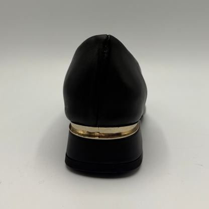 Back view of a black leather pump with a slouchy accent on the pointed toe and a gold accent on the heel