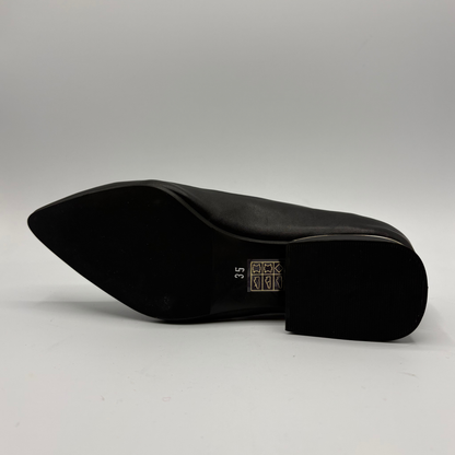 Bottom view of a black leather pump with a slouchy accent on the pointed toe and a gold accent on the heel
