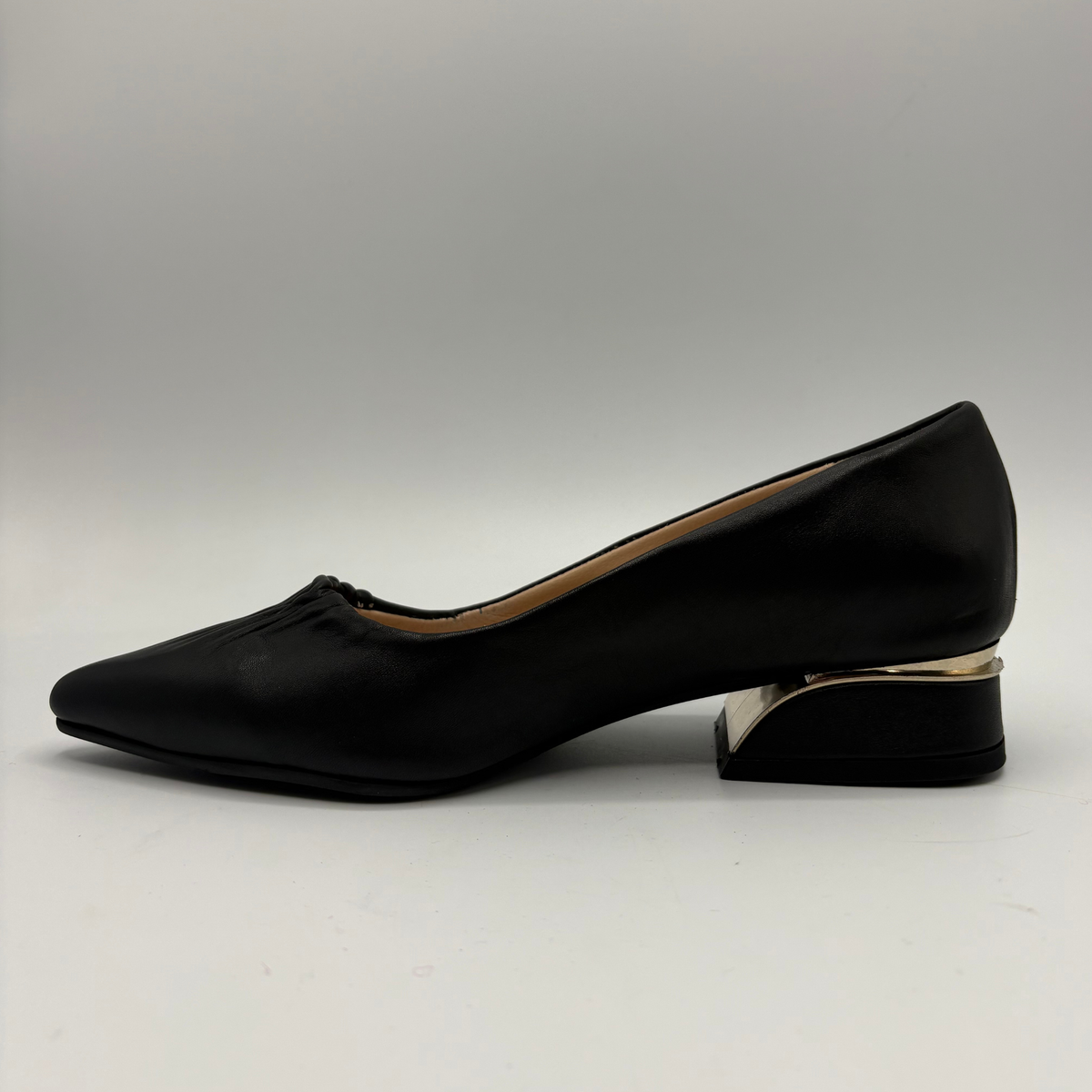 Left facing view of a black leather pump with a slouchy accent on the pointed toe and a gold accent on the heel