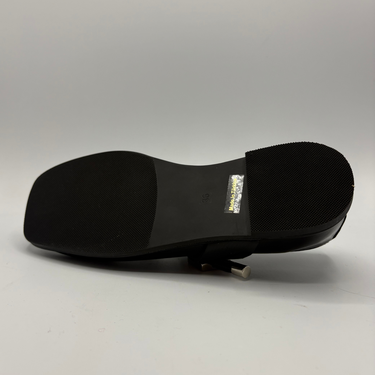 Bottom view of a black leather ballet flat shoe with silver accents