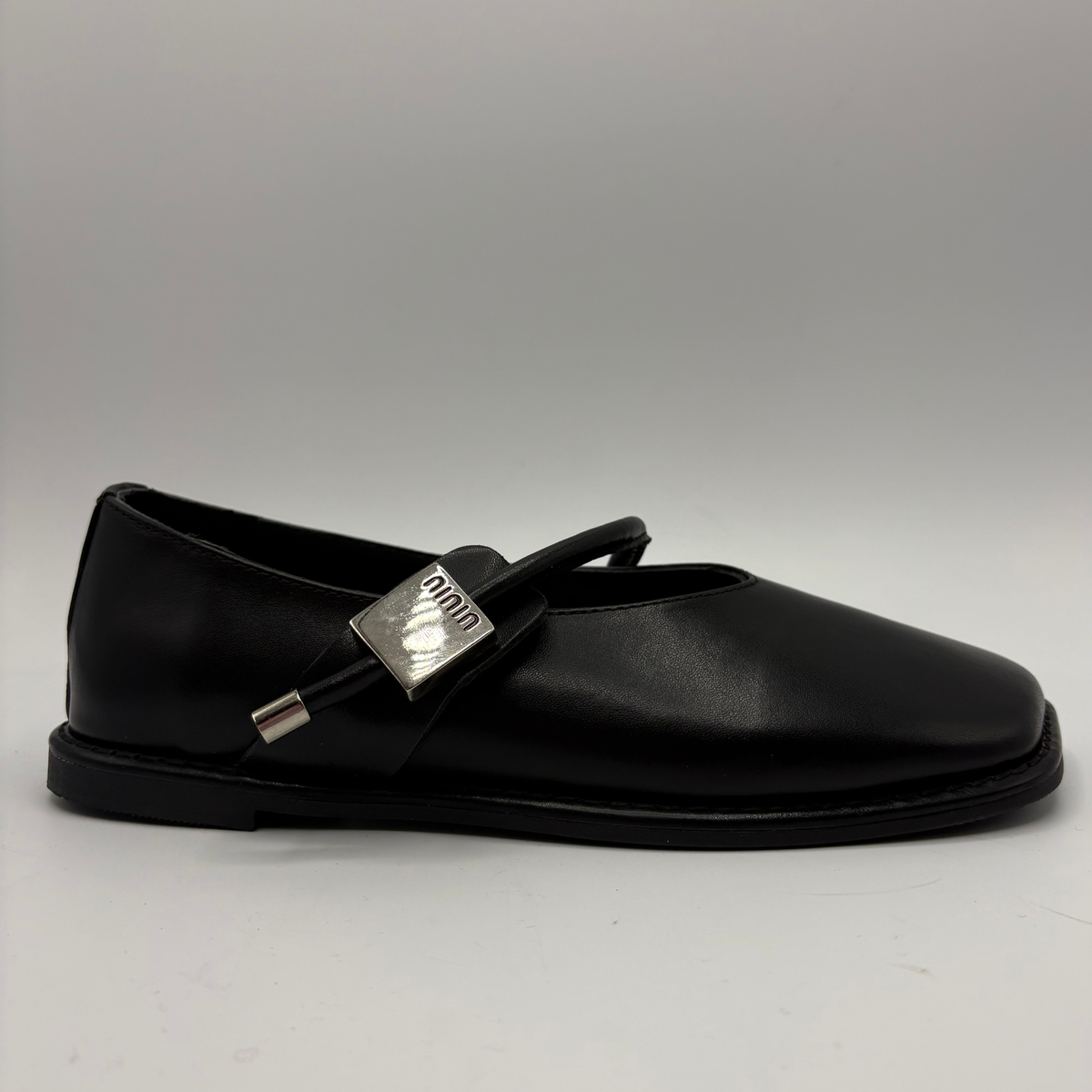 Right facing view of a black leather ballet flat shoe with silver accents