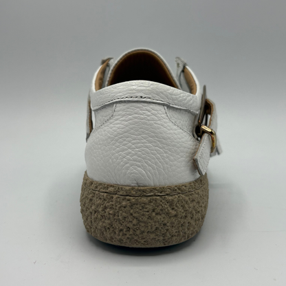 Back view of a white leather shoe with a rubber outsole and a buckle closure