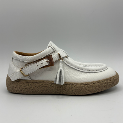 Right facing view of a white leather shoe with a rubber outsole and a buckle closure