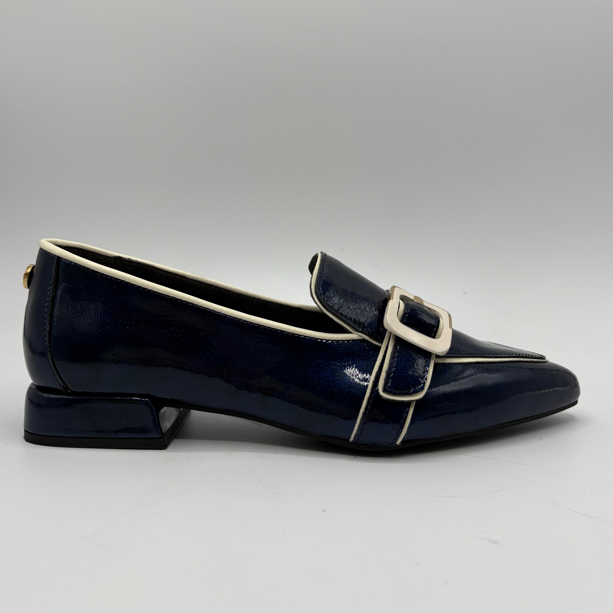 Right facing view of a dark blue patent leather loafer with a pointed toe and a buckle strap accent