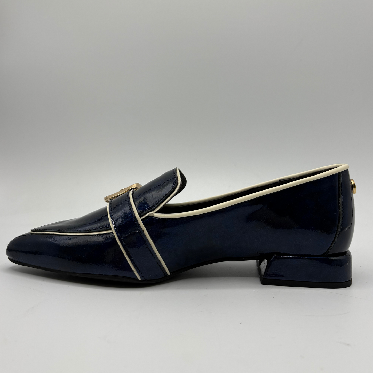 Left facing view of a dark blue patent leather loafer with a pointed toe and a buckle strap accent
