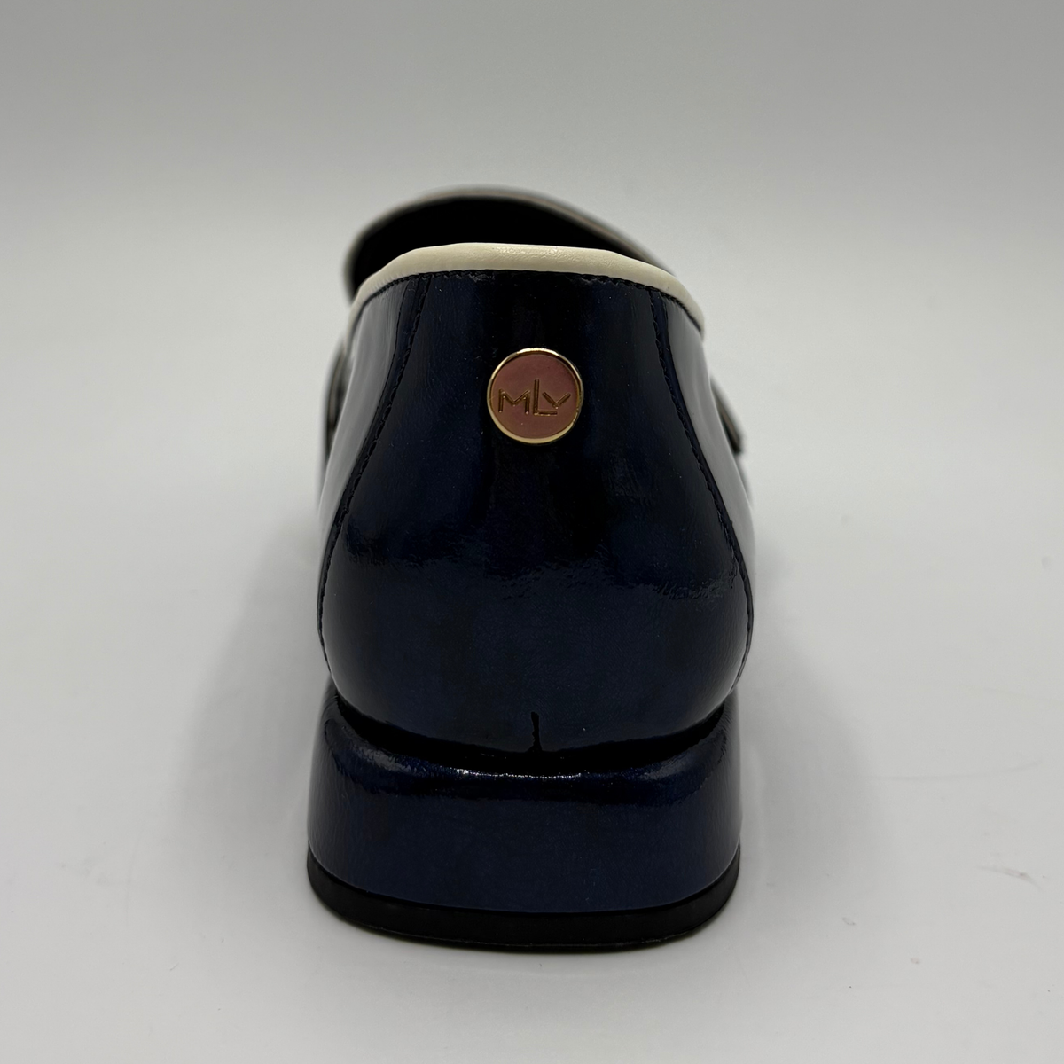Back view of a dark blue patent leather loafer with a pointed toe and a buckle strap accent