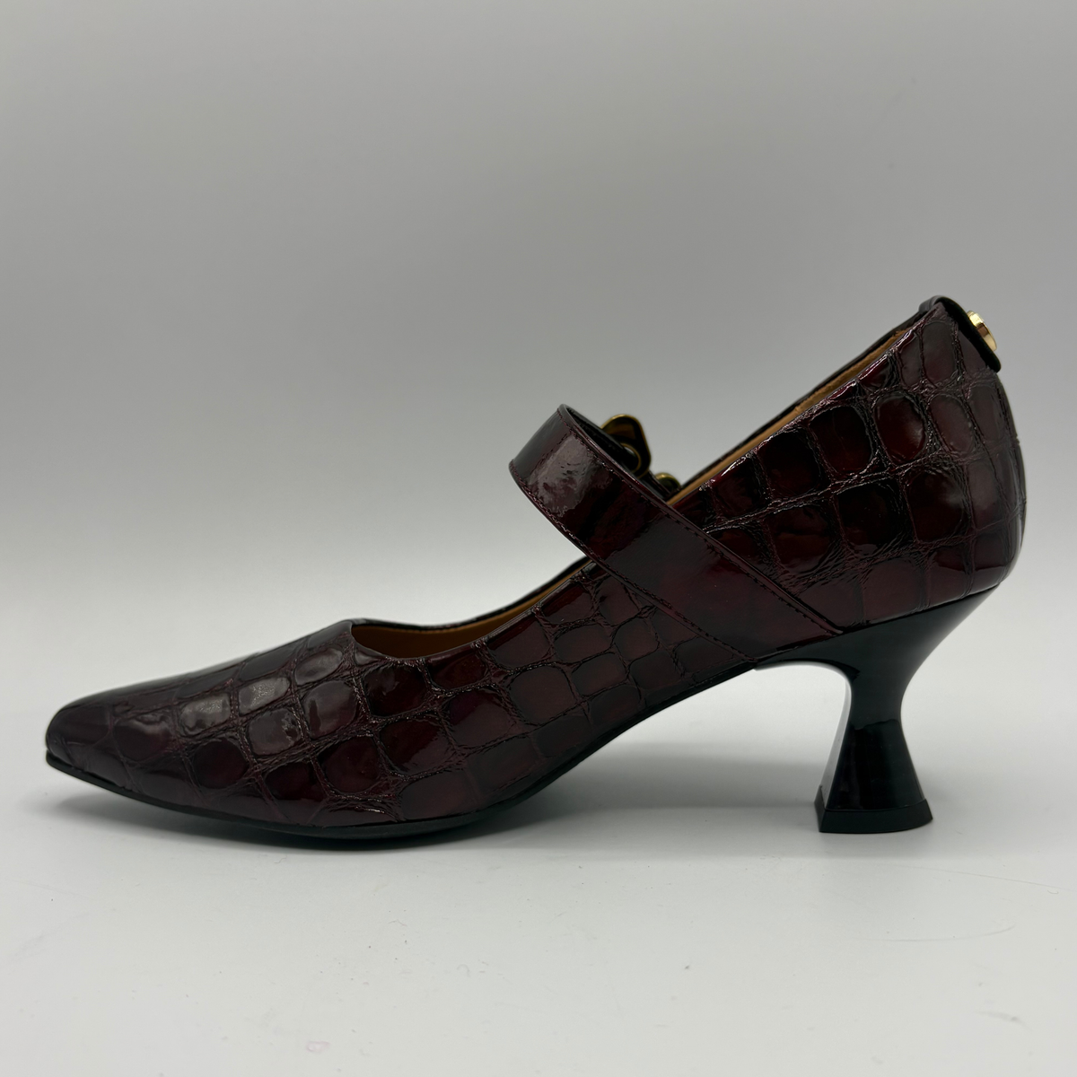 Left facing view of a burgundy high heeled shoe with a flared heel and gold buckle