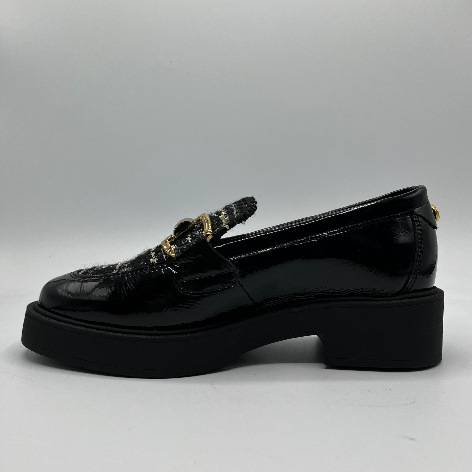 Black loafers with decorative elements on a gray background