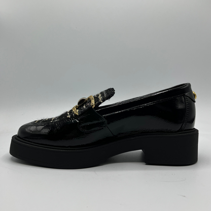 Black loafers with decorative elements on a gray background