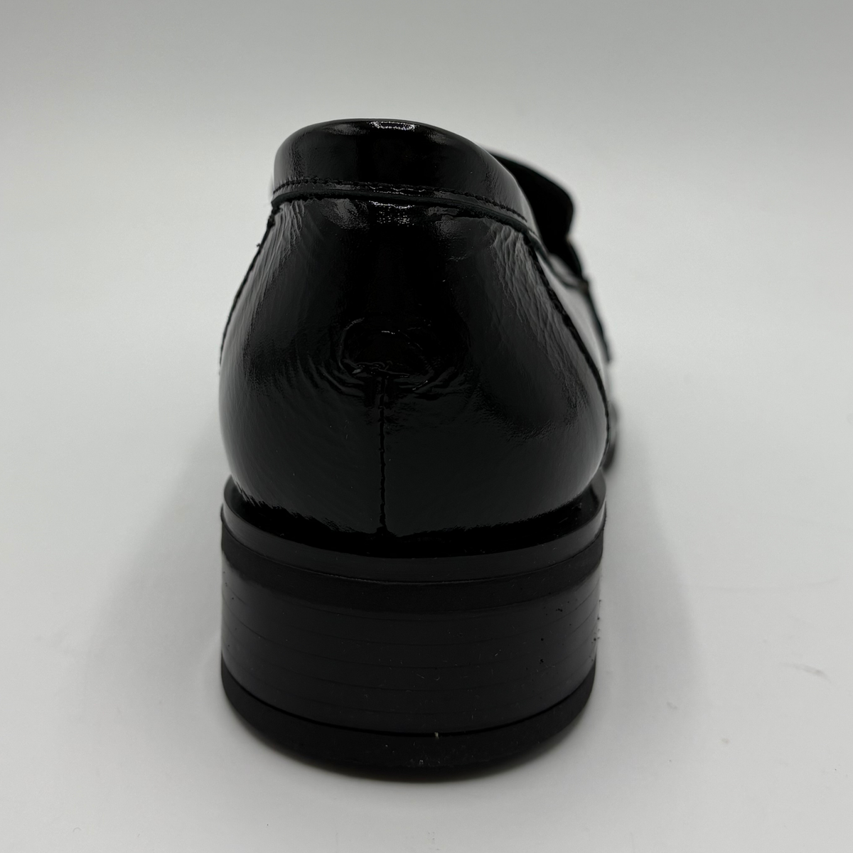 Back view of a black leather loafer with an animal print accent on the toe box and chain detail.