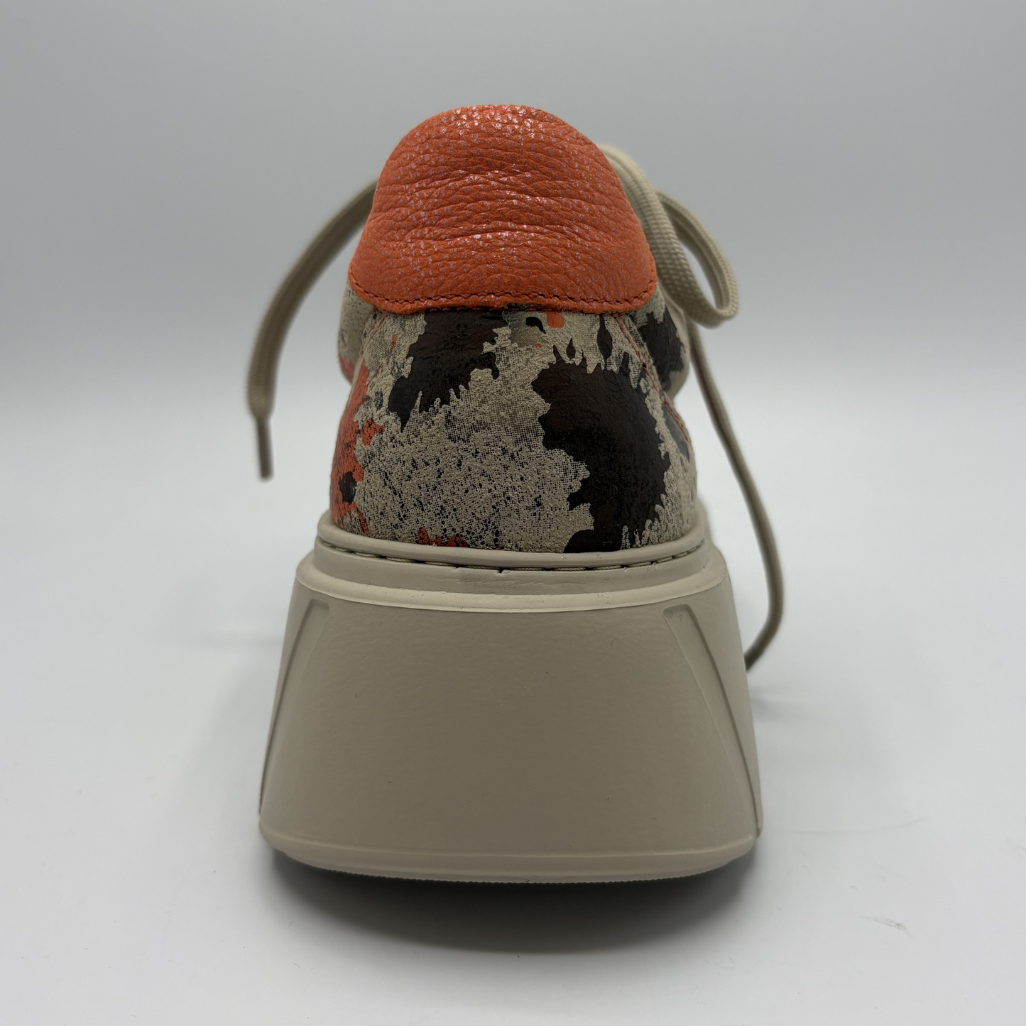 Sneaker with a textured orange top and beige sole on a white background