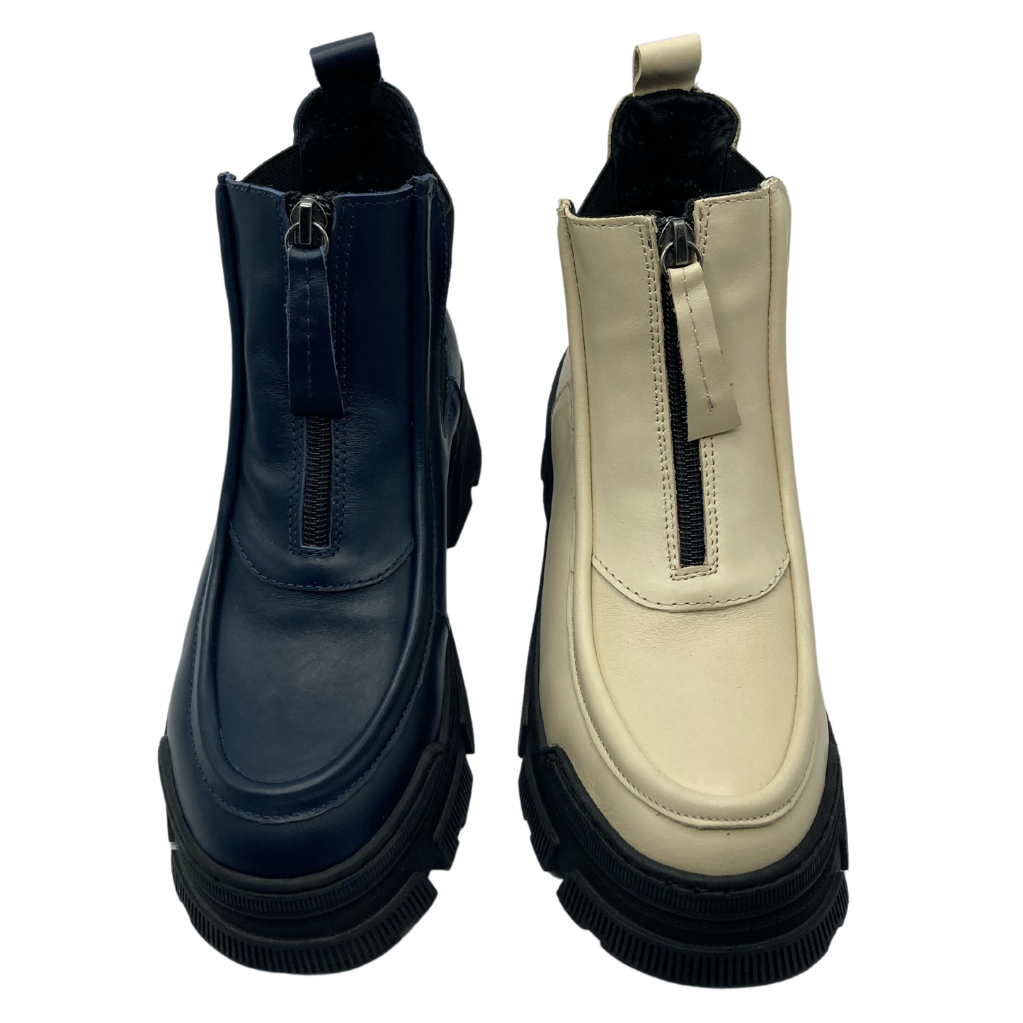 View of a pair of leather short boots one blue and one beige. Both with chunky black rubber outsoles and black upper zippers