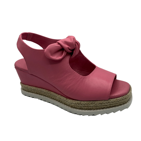45 degree angled view of pink leather wedge sandal with slingback strap and bow detail