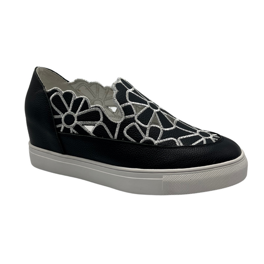 45 degree angled view of leather wedge sneaker with hidden wedge, cut out and embroidered upper and white rubber outsole.