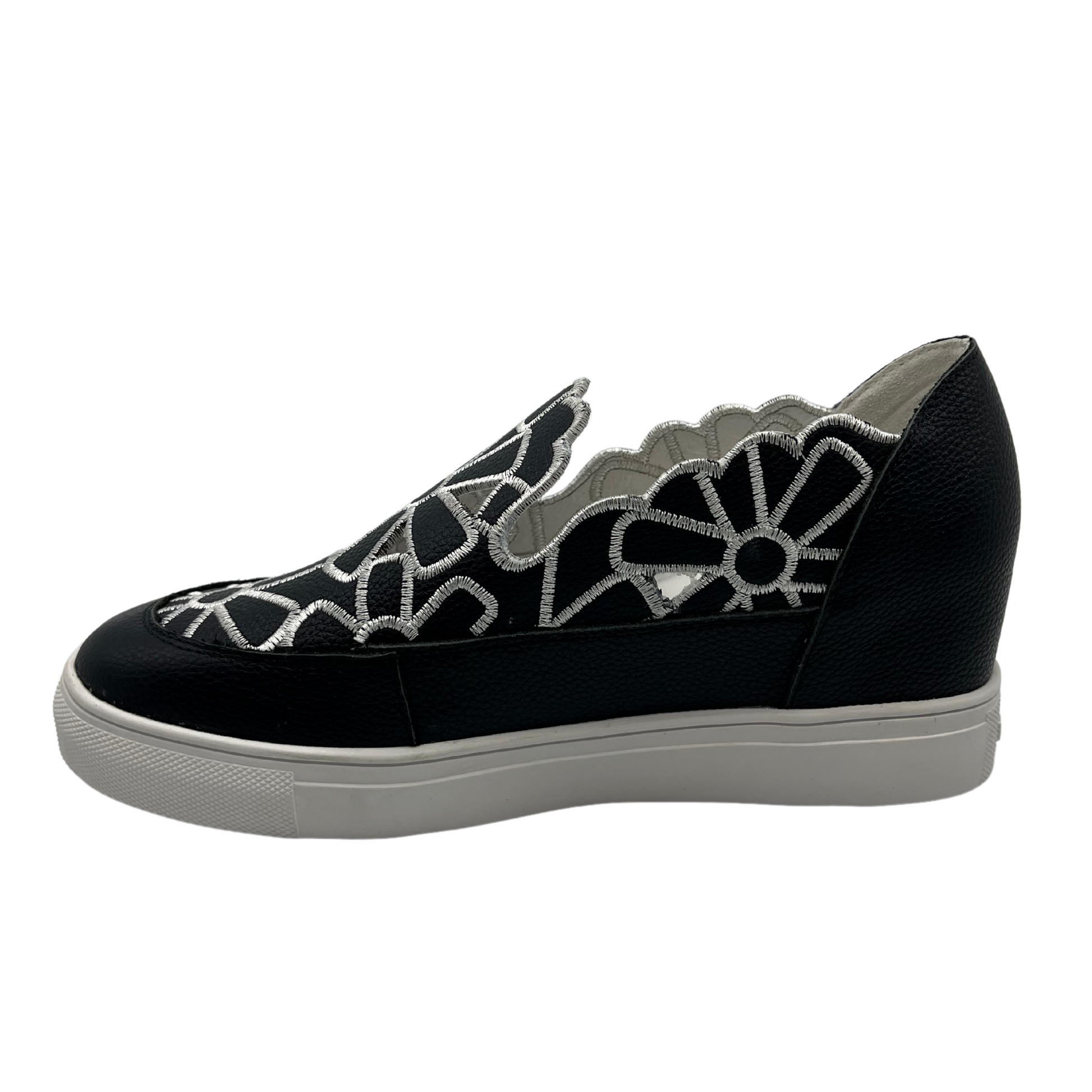 Left facing view of leather wedge sneaker with hidden wedge, cut out and embroidered upper and white rubber outsole.