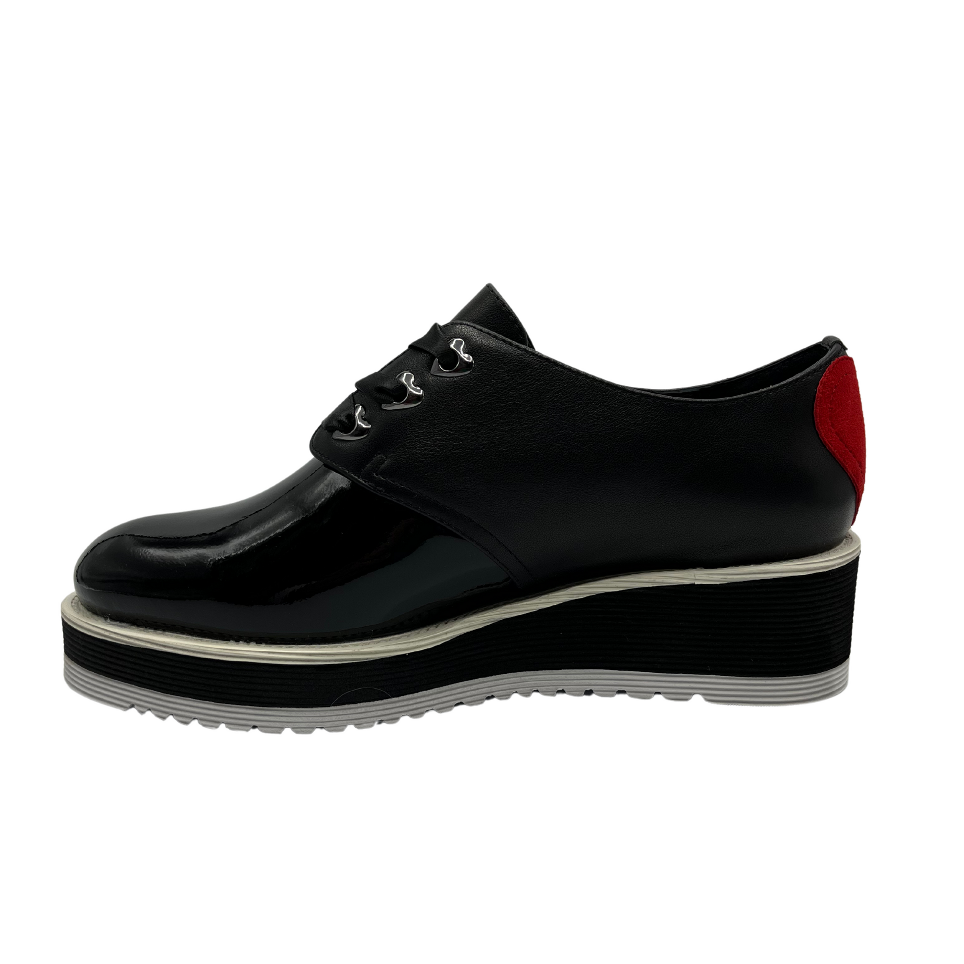 Left facing view of black patent leather shoe with red heart on the heel, ribbon laces and thick rubber outsole.