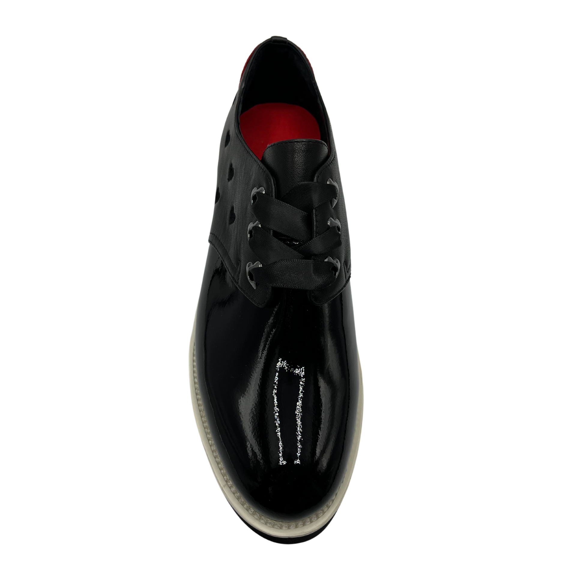 Top view of black patent leather shoe with red heart on the heel, ribbon laces and thick rubber outsole.