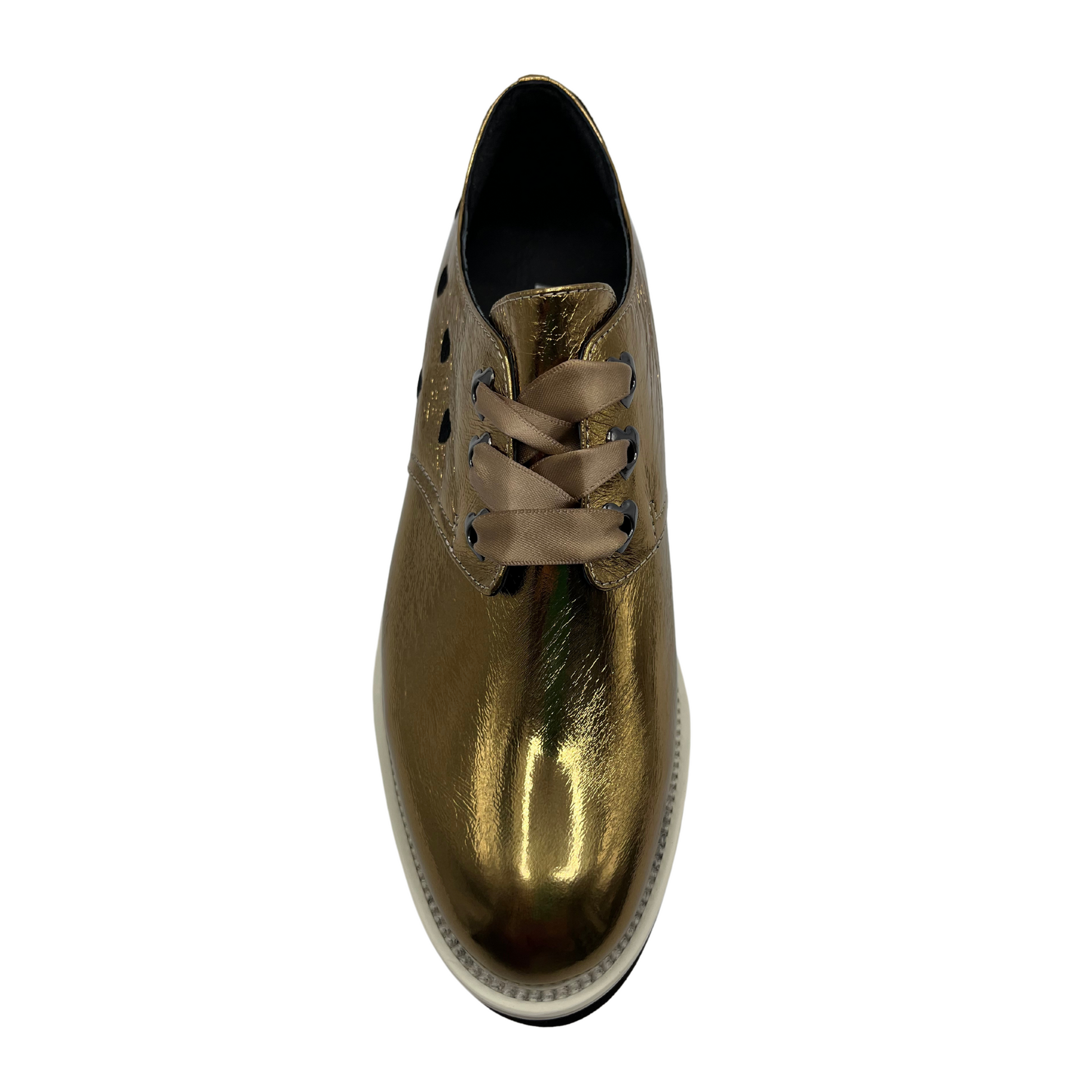 Top view of gold patent leather shoe with a black heart on the heel, ribbon laces and thick rubber outsole.