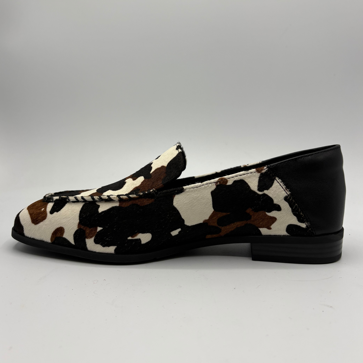Left facing view of a cow print suede loafer with a low heel