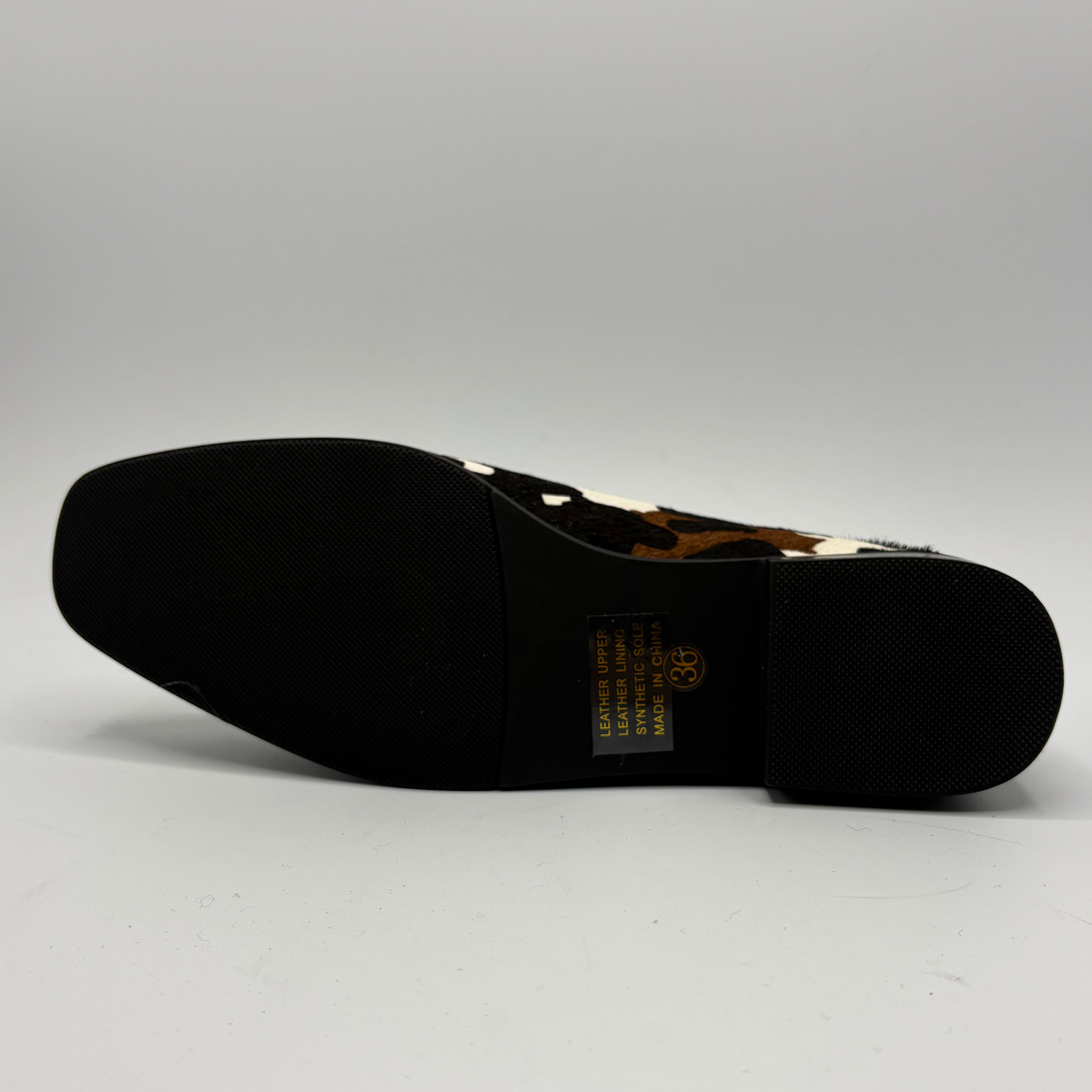 Bottom view of a cow print suede loafer with a low heel
