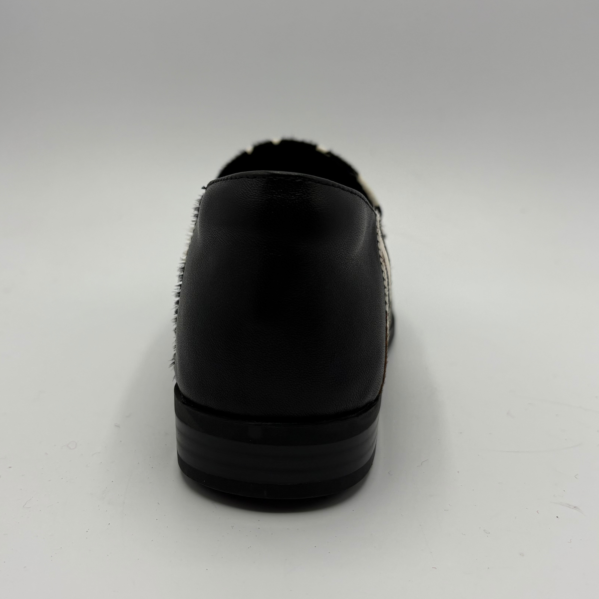 Back view of a cow print suede loafer with a low heel