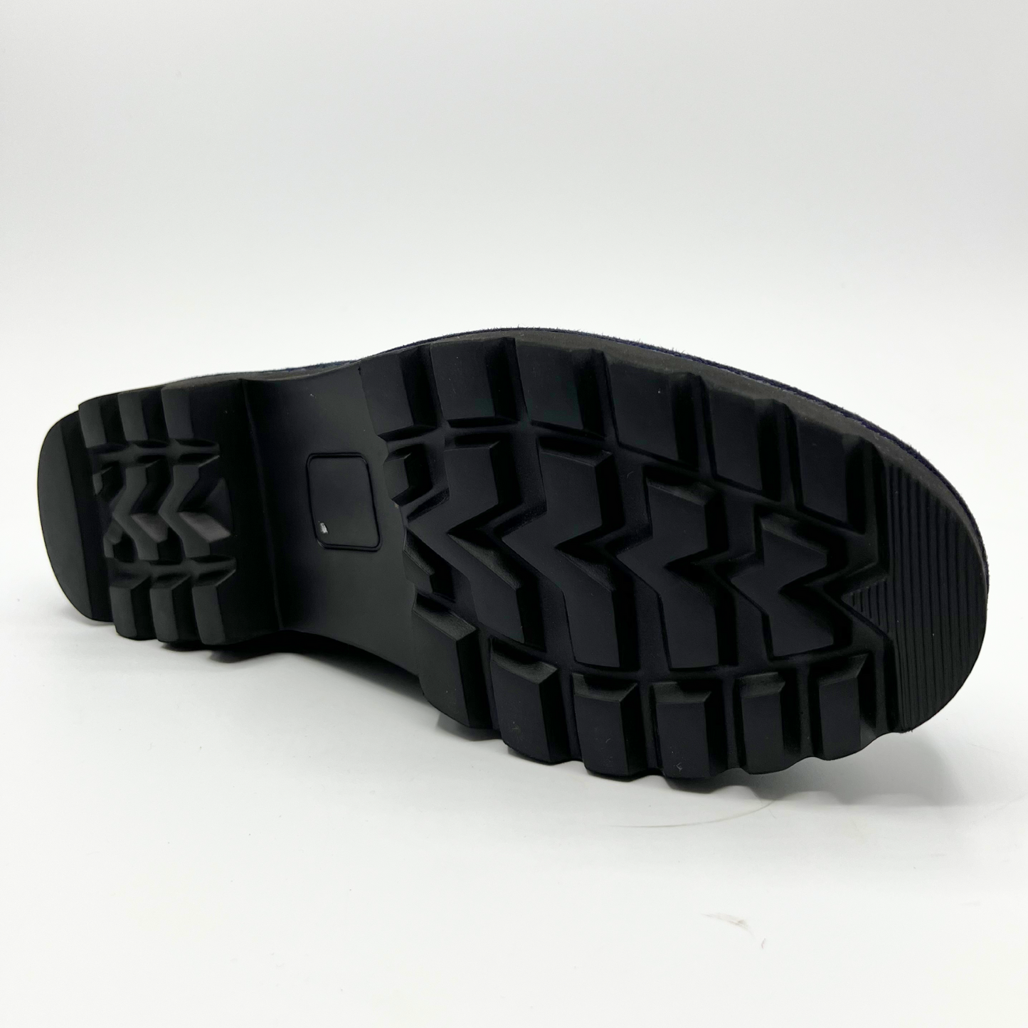 Bottom view of navy suede loafer with thick rubber outsole and gold/black detail on upper