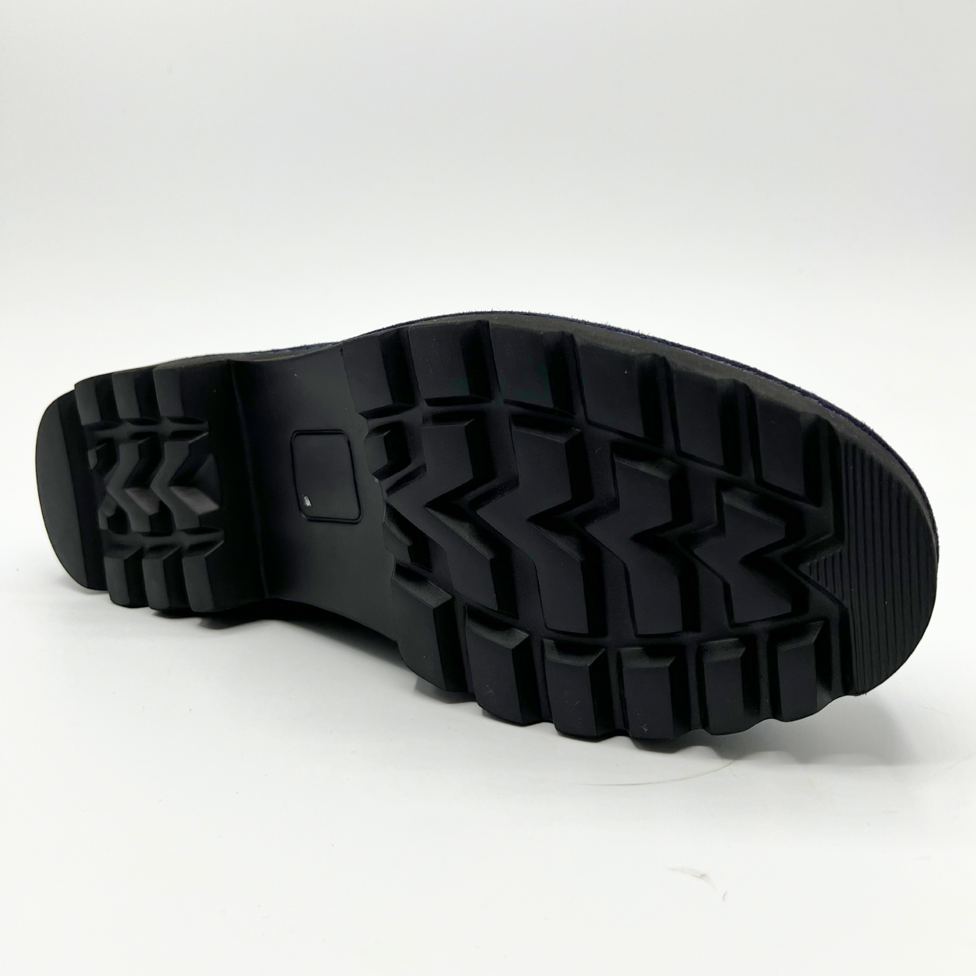 Bottom view of navy suede loafer with thick rubber outsole and gold/black detail on upper