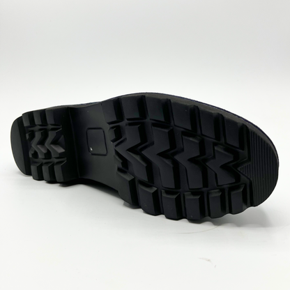 Bottom view of navy suede loafer with thick rubber outsole and gold/black detail on upper
