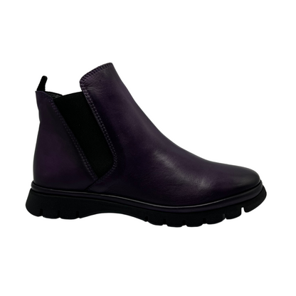 Right facing view of dark purple leather short boot with slim black outsole and pull on heel tab. Elastic side gore with rounded toe