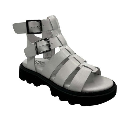 45 degree angled view of white leather gladiator sandal with black rubber outsole. Lined footbed and double buckle straps