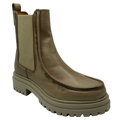 45 degree angled view of beige leather short boot with lug rubber outsole, elastic side gore and pull on tab